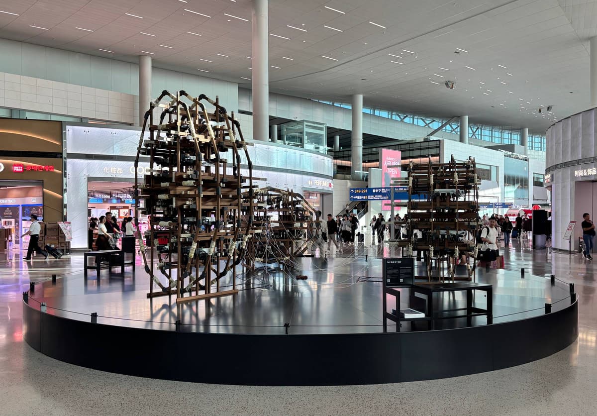 Jung Uk Yang's kinetic sculpture of wooden frames strung with thread, on a round black plinth in the departure hall of Incheon Airport Terminal 2