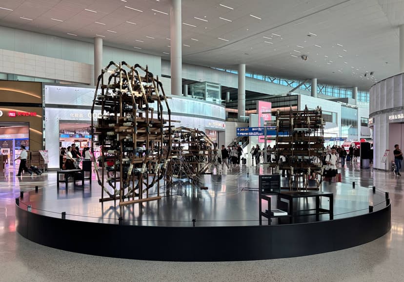 Jung Uk Yang's kinetic sculpture of wooden frames strung with thread, on a round black plinth in the departure hall of Incheon Airport Terminal 2