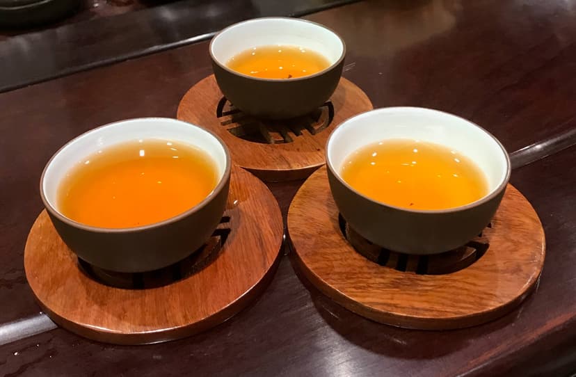 Three small cups of tea on carved wooden coasters