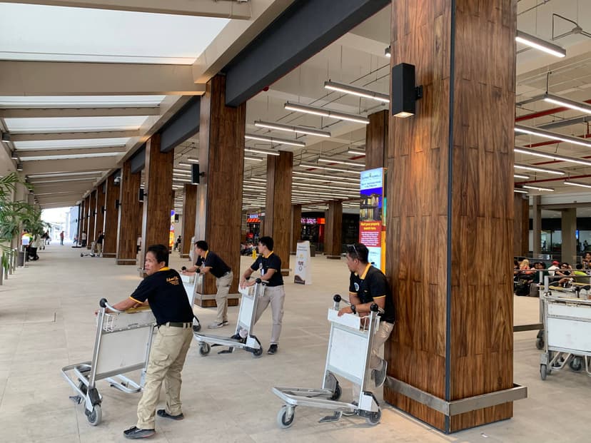Porters waiting with luggage trolleys outside an airport terminal