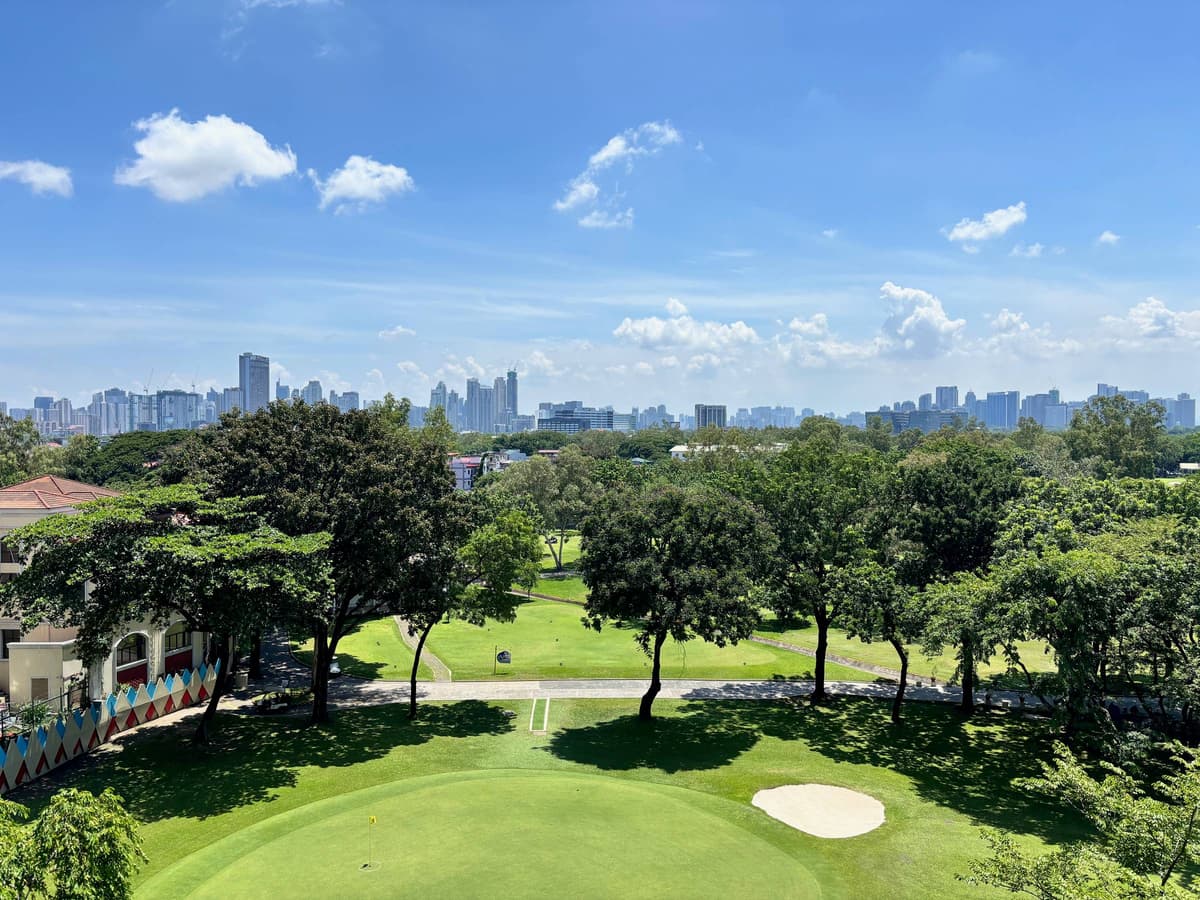 A golf course green and fairway with a city skyline on the horizon
