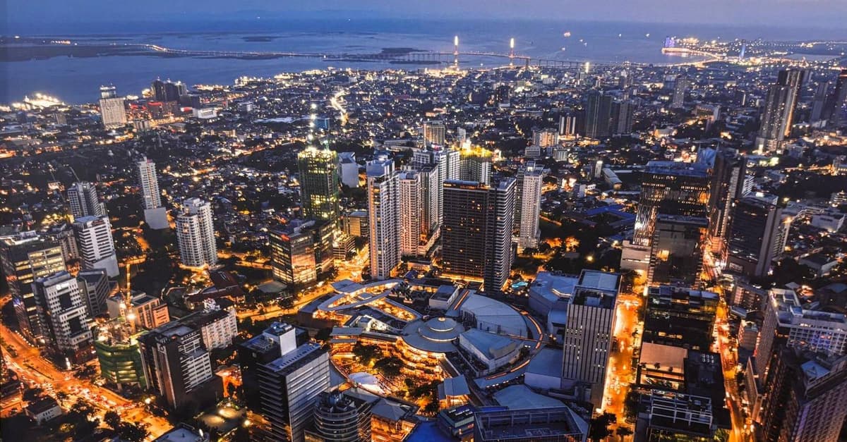 Aerial view of Cebu City lit up at dusk, with the sea beyond