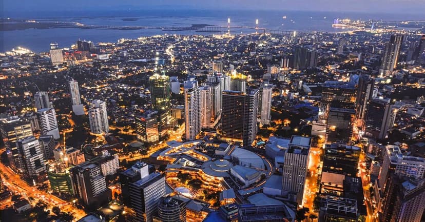 Aerial view of Cebu City lit up at dusk, with the sea beyond
